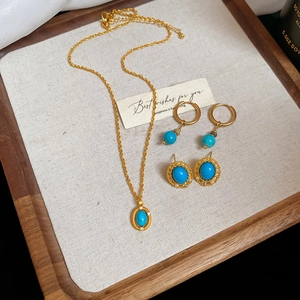 Macro shot of turquoise jewelry set with vintage gold necklace and earrings on a tray