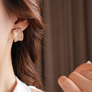 Gros plan d'élégantes boucles d'oreilles fleurs roses plaquées or portées par un mannequin