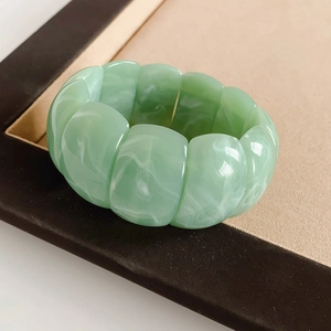 Detail of wide light green acrylic beaded bracelet with elegant marble textures