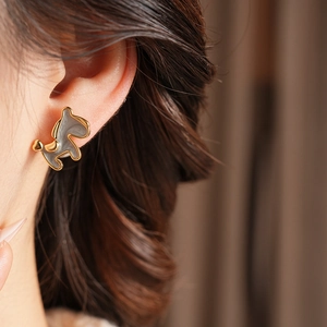 Detail of 18K gold plated pony earrings with blue enamel inlay on a female model