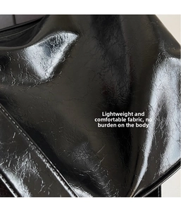 Detail shot of the black crinkled glossy leather texture on this stylish shoulder bag