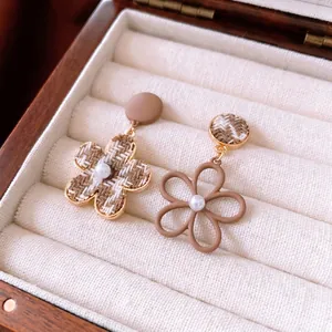 Orecchini asimmetrici a fiori in tessuto e perle in una scatola portagioie vintage