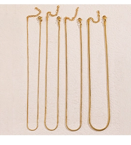Detail view of four golden stainless steel snake chains with lobster clasps and extenders
