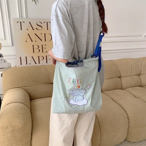 Close-up of elephant embroidery and adjustable blue strap on mint green tote bag