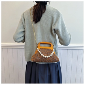 Close-up of brown tweed bag with wooden handle and decorative pearl chain detail