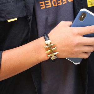 Minimalist black braided leather bracelet with gold metal nail accents on wrist