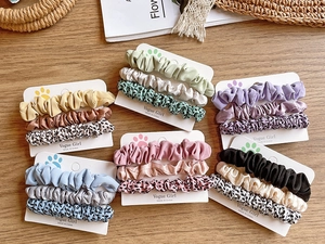 Detailed set of 18 leopard print fabric hair scrunchies on a natural wooden tabletop