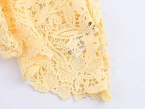 Close-up of intricate hollow floral lace pattern on yellow sleeveless top and skirt set