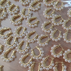 Boucles d'oreilles perles dorées en forme de U style rétro sur fond bois naturel