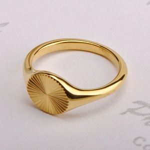Macro shot of 18K gold plated signet ring with sunburst engraving and polished finish