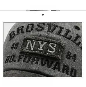 Macro detail of 3D embroidery and vintage washed denim texture on a dark gray baseball cap