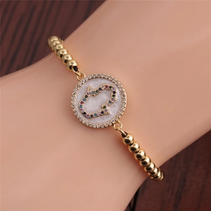Detail of gold beaded bracelet with colorful zircon Hamsa Hand charm on model wrist