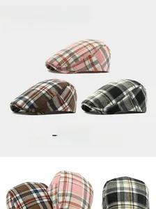 Detailed close-up of three classic plaid beret hats in pink, brown, and grey vintage patterns