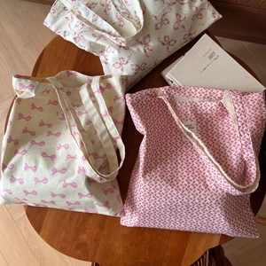 Détail de sacs cabas en coton avec nœuds roses et motifs floraux sur table en bois