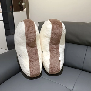 Close-up of soft plush bread cushions with cute minimalist eyes on a grey sofa