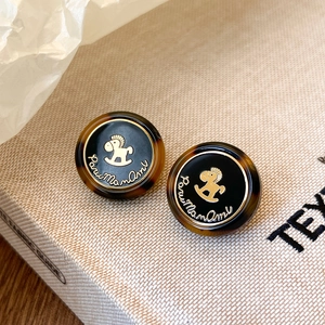 Détail de boucles d'oreilles en résine vintage avec motif cheval à bascule doré