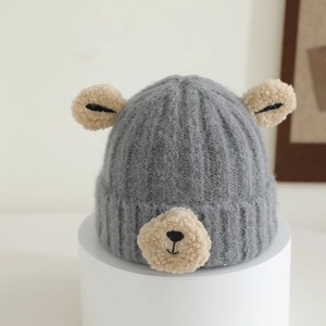 Detailed view of grey knitted baby hat with white teddy bear ears and soft textures