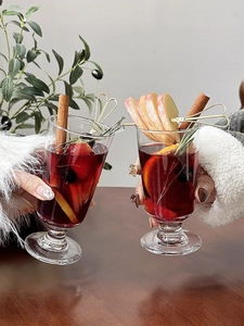 Close-up of two glass wine goblets clinking with hot mulled wine and fresh winter fruits