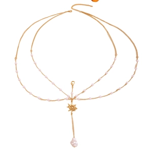Detail of gold body chain with pink beads, sun pendant, and baroque pearl drop