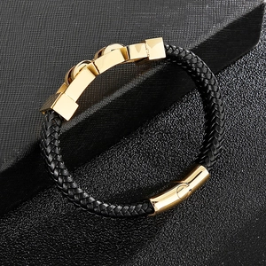 Detail of black braided leather bracelet with high-gloss gold metallic clasp on display
