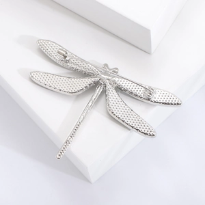 Vintage silver dragonfly brooch with textured wings shown from the back with secure pin clasp