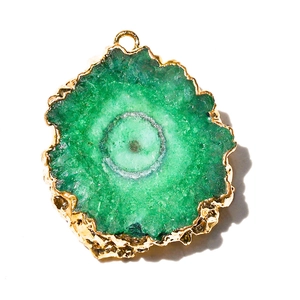 Macro shot of green agate slice pendant with polished gold plated rim and natural core