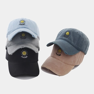 Detail view of washed cotton baseball caps with sunshine embroidery and distressed brims