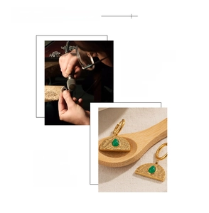 Detail of 18k gold plated hammered earrings with green teardrop gemstones on wood