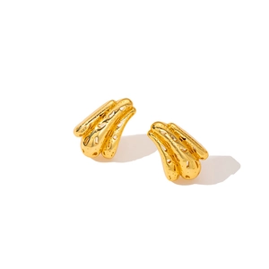 Detailed close-up of golden hollow irregular earrings with textured relief and artistic design
