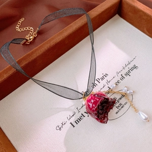 Detail of red rose pendant on black lace choker with white pearl drop and golden clasp
