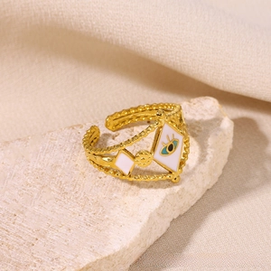 Detailed macro view of gold evil eye ring with white enamel on a stone surface