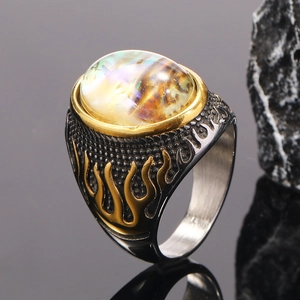 Macro detail of punk rock ring with gold flame relief and iridescent abalone stone