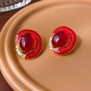 Detail of vintage oval stud earrings with red enamel scales and rhinestone borders