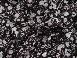 Detail shot of elegant floral chiffon fabric featuring a tied bow and pink petal patterns