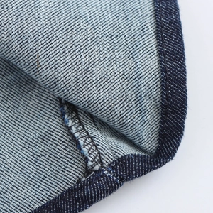 Dettaglio macro del tessuto denim blu scuro e delle cuciture su un abito di jeans