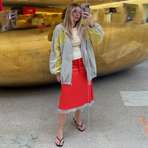 Détail de la jupe midi rouge avec bordure en dentelle grise et taille à cordon élégante
