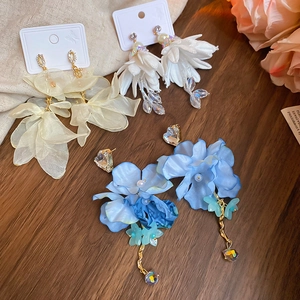Detailed close-up of chiffon flower tassel earrings with crystals on a wooden background