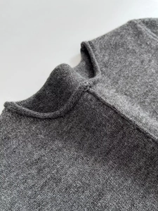 Close-up of the soft gray knitted neckline showing fine wool texture and stitching
