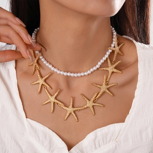 Close-up of double-layer necklace with faux pearls and textured golden starfish charms
