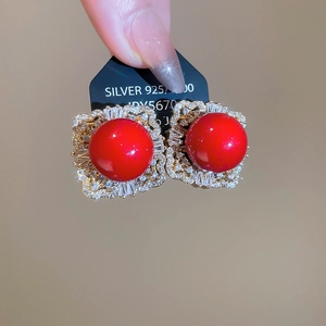 Macro shot of 925 silver stud earrings with large red pearls and sparkling rhinestones
