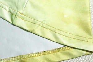 Détail macro d'une couture overlock à double aiguille sur une robe dégradée vert citron