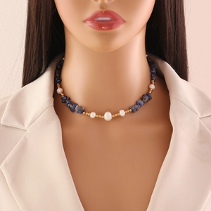 Detail of natural blue stone and pearl necklace worn on a model with a beige blazer