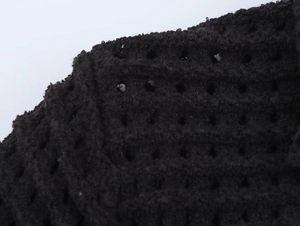 Primo piano dettagliato del tessuto a maglia traforato nero con texture di frange e trama