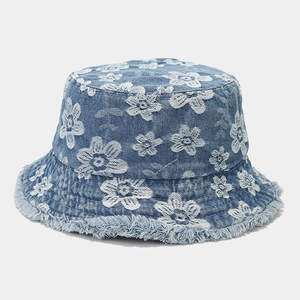 Detailed macro view of white floral embroidery and frayed edges on denim bucket hat