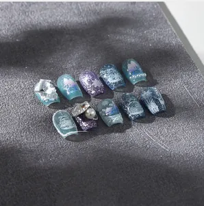 Detail of Christmas nail art stickers featuring blue gradient, snowflake patterns and 3D pearls