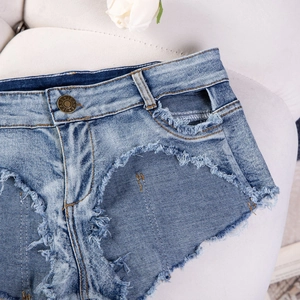 Dettaglio degli shorts in denim a vita alta con orli sfrangiati e bottone in metallo