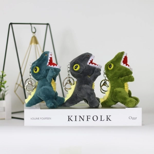 Three colorful plush dinosaur keychain pendants standing on decorative books in detail
