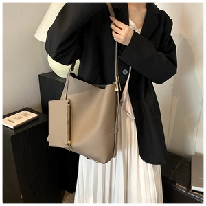 Detail of khaki leather tote bag showing side metal buckle and matching pouch