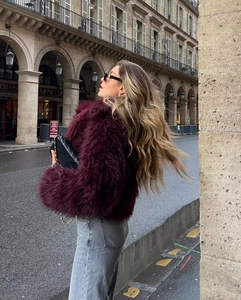 Street style εμφάνιση με γυναικείο μπορντό γούνινο παλτό και γκρι τζιν παντελόνι
