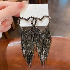 Detailed close-up of long heart tassel earrings with dark crystal pavé on a jewelry card